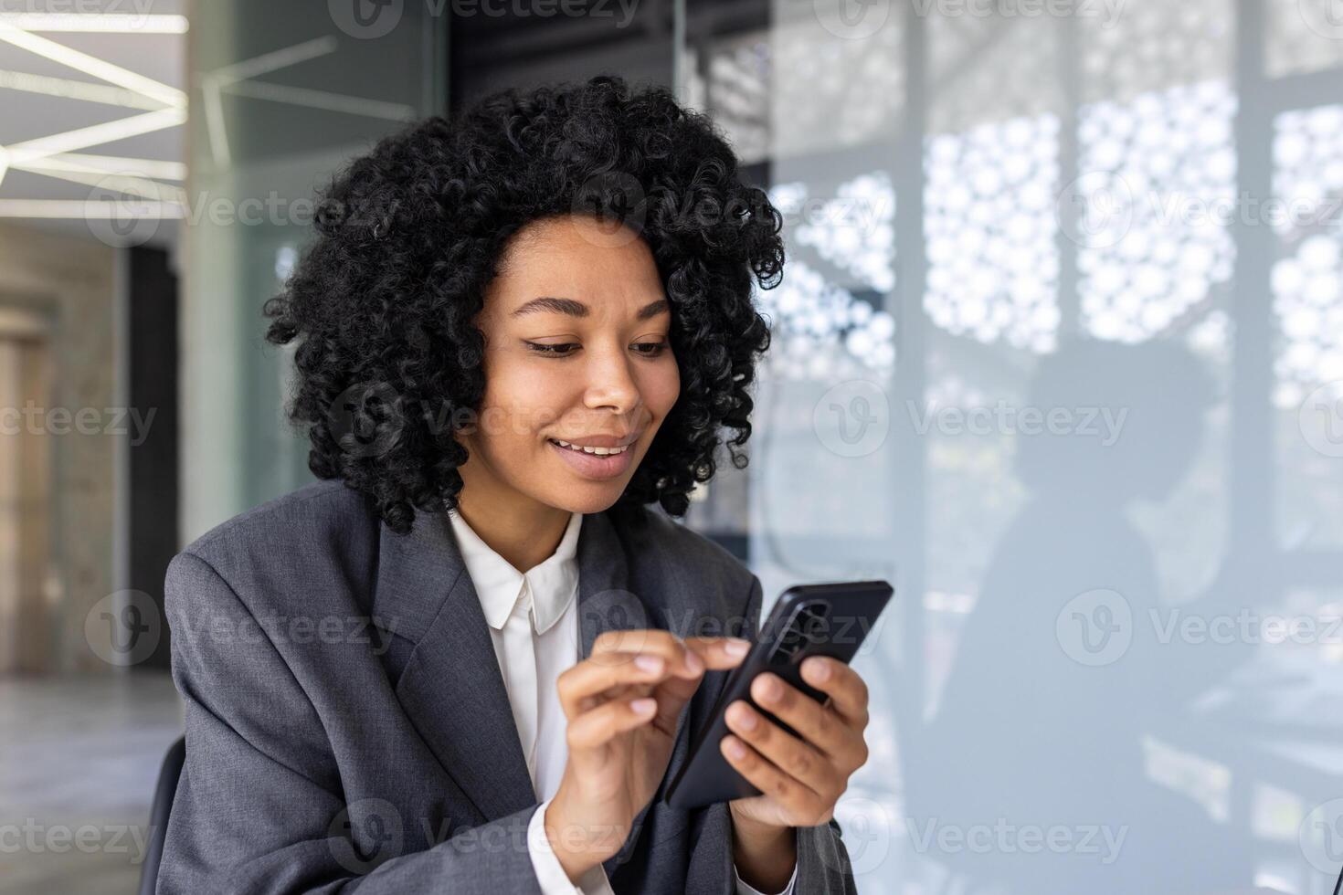 réussi femme d'affaires les usages téléphone intelligent à l'intérieur Bureau fermer, souriant employé les usages app sur téléphone, les types messages et parcourt l'Internet pages en ligne. photo