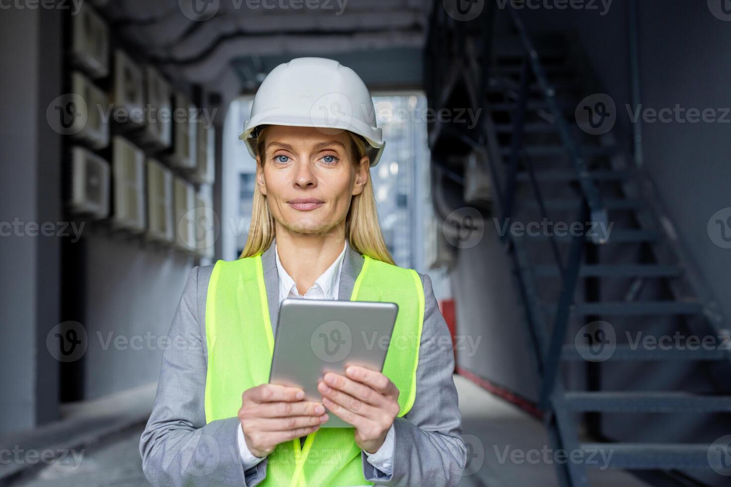 portrait de une Jeune femelle ingénieur, constructeur, architecte portant une difficile chapeau, réfléchissant gilet et en portant une tablette. il regards sérieusement dans le caméra. photo