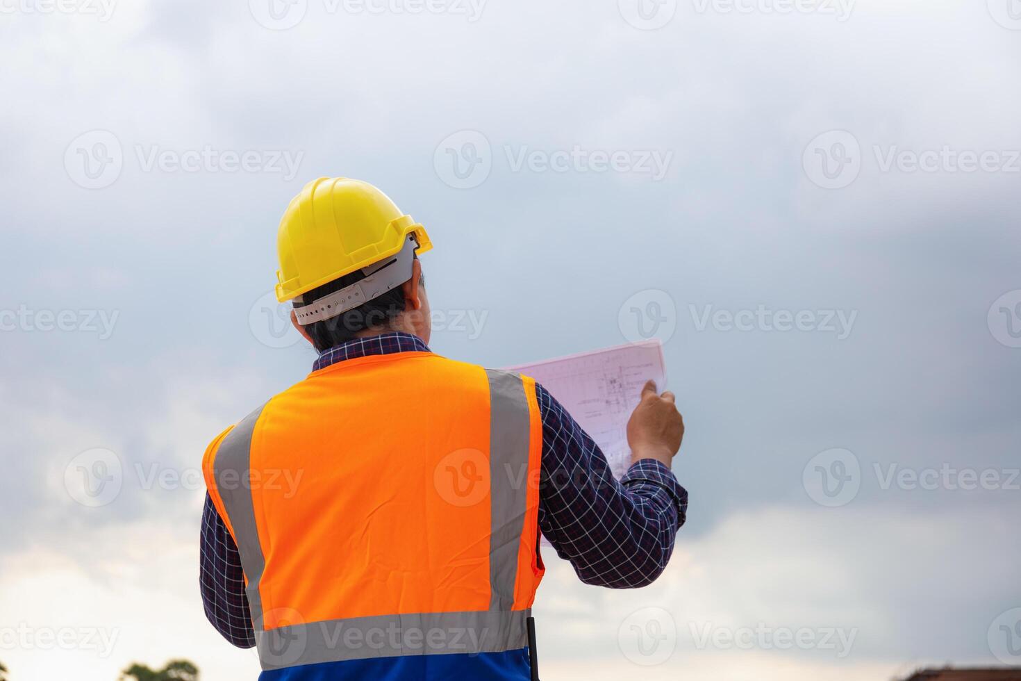 ingénieur homme avec plan vérification projet à bâtiment placer, contremaître ouvrier dans difficile Chapeaux sur construction site photo