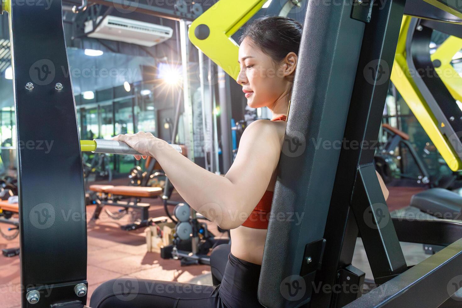 asiatique femme travail en dehors dans le salle de sport, Jeune aptitude femmes exécuter exercice avec machine d'exercice physique dans le Gym photo