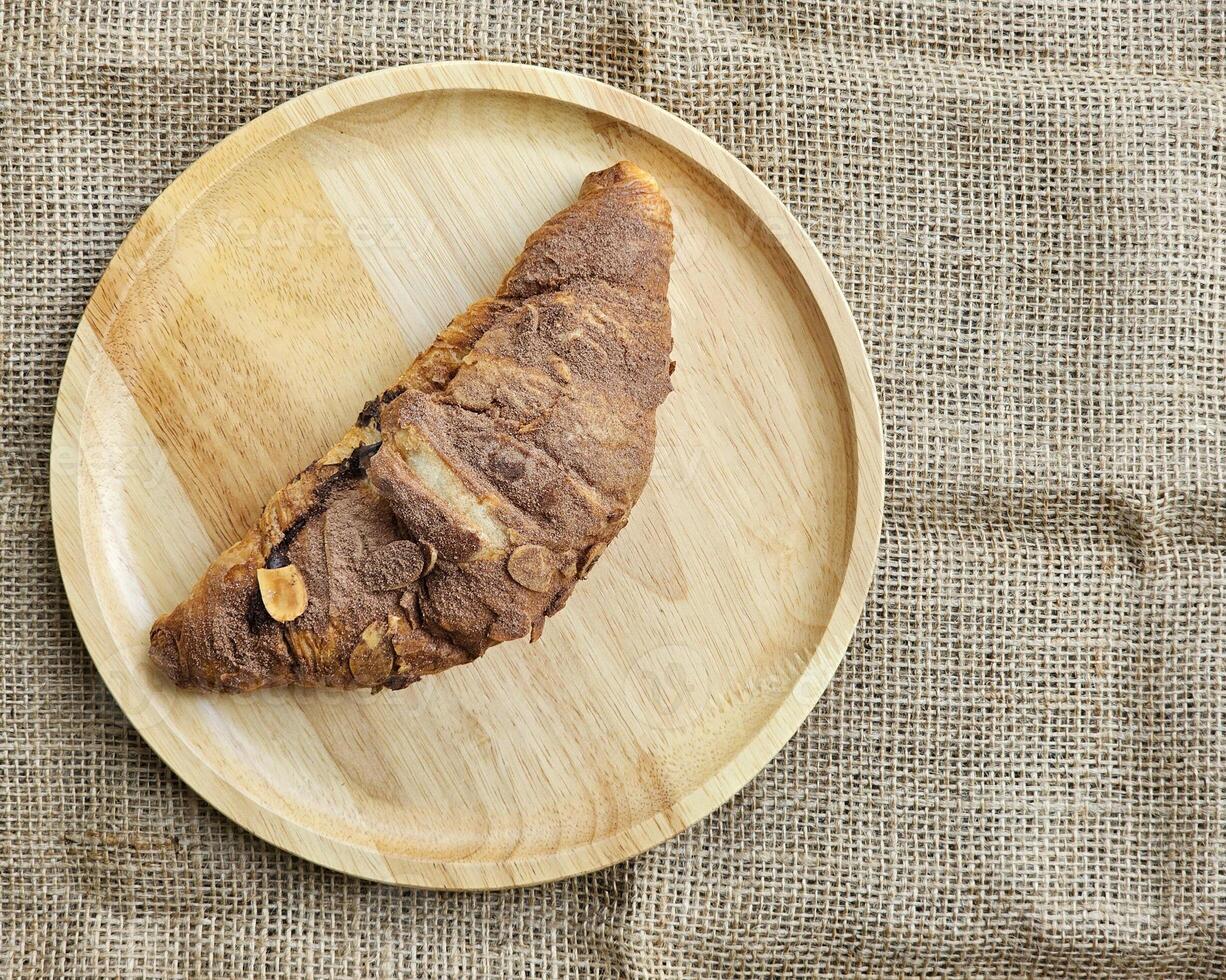 Chocolat des croissants décoré avec cacao poudre et amandes sur une en bois plaque. Haut vue photo