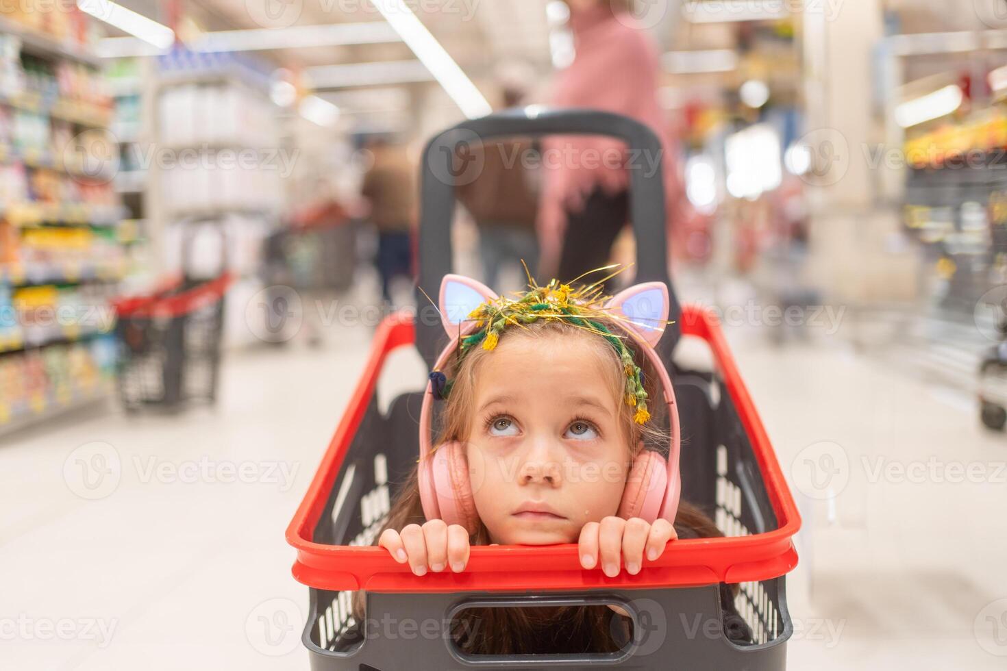 réfléchi fille portant écouteurs dans achats Chariot à supermarché photo