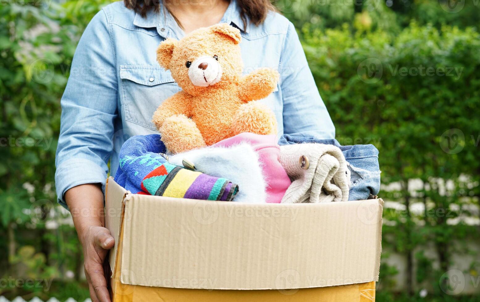 bénévole collecte tissu et poupée dans papier carton boîte à donner. photo