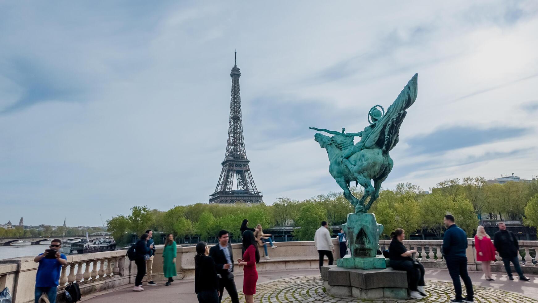 diverse touristes profiter printemps près le Eiffel la tour et une bronze statue dans Paris, France, sur avril 14ème, 2024, adapté pour Voyage et culturel thèmes photo