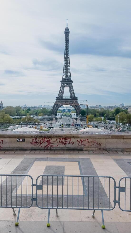 vue de le iconique Eiffel la tour pris de une graffiti orné avantage indiquer, avec barrières dans le premier plan, capturer le essence de Paris, France, sur avril 14ème, 2024 photo