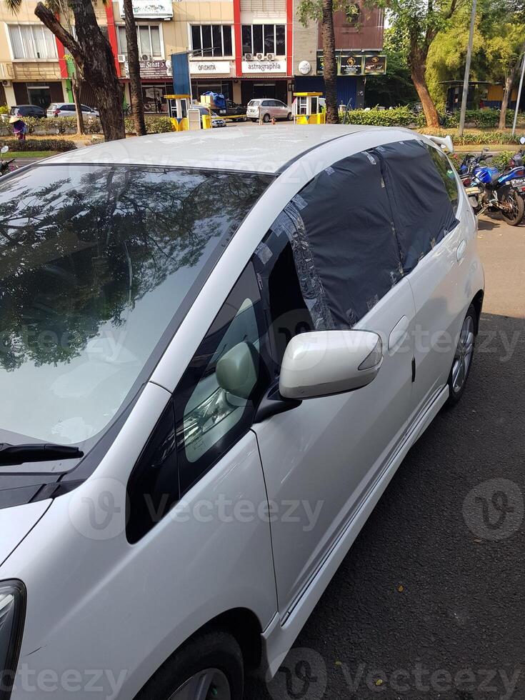 brisé verre de une blanc honda le jazz voiture cette a été cassé dans par voleurs. car le de face et arrière pare-brise étaient cassé photo