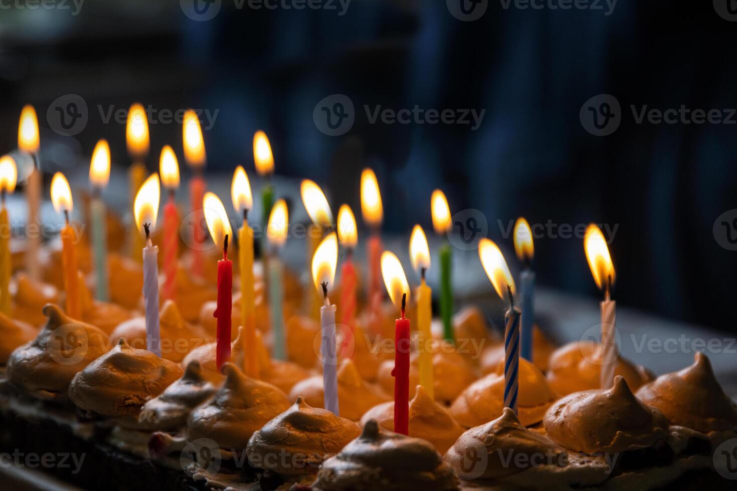 fermer 15 coloré allumé bougies à le anniversaire fête à maison. grand fait maison Chocolat gâteau, décoré avec meringues et fouetté crème. fête concept. sélectif se concentrer. photo