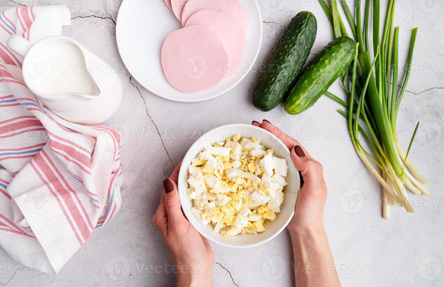 préparation étape par étape de la soupe froide d'okroshka avec des saucisses, étape 3 - ajout d'œufs durs hachés dans un bol vue de dessus photo