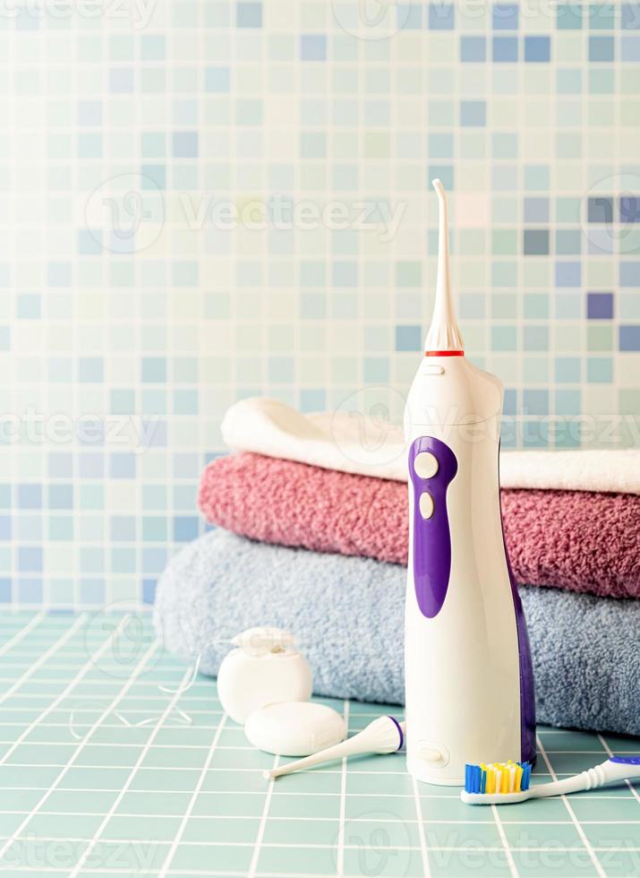 irrigateur de dents électronique, brosses à dents et un tas de serviettes vue de face copie espace photo