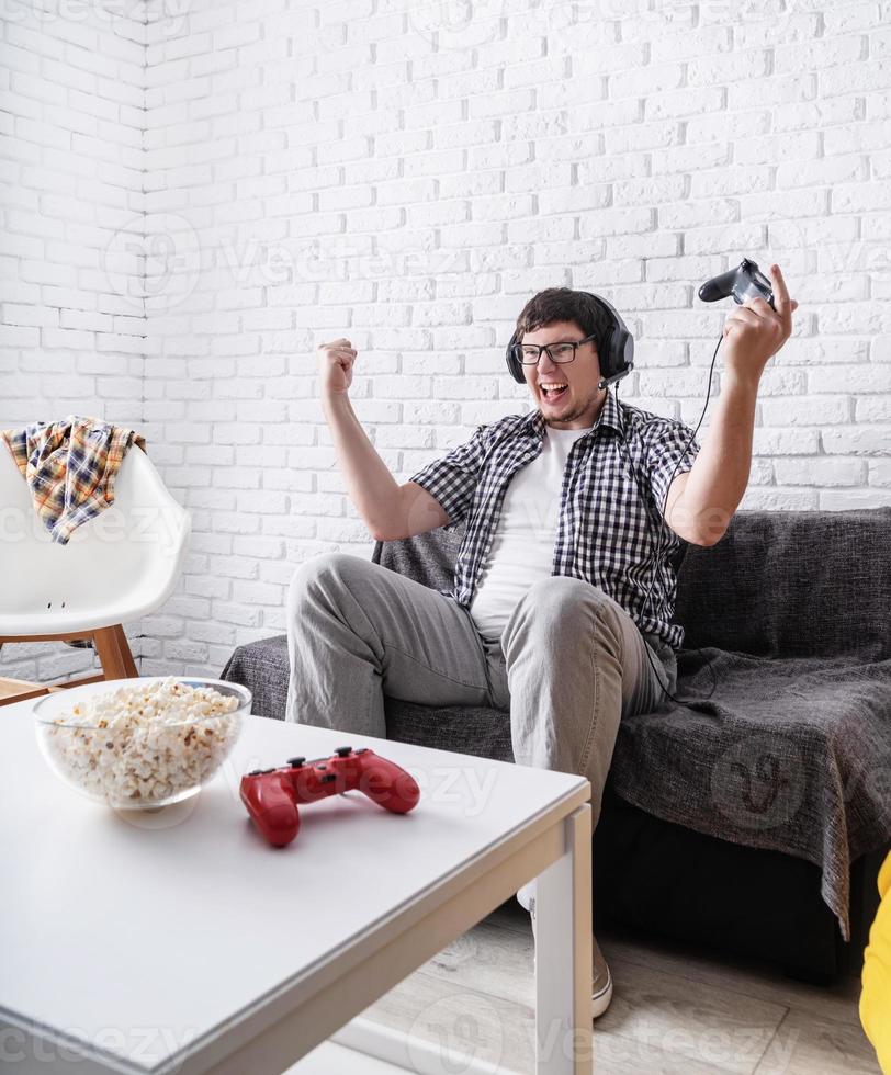 jeune homme excité jouant à des jeux vidéo à la maison profitant de sa victoire photo