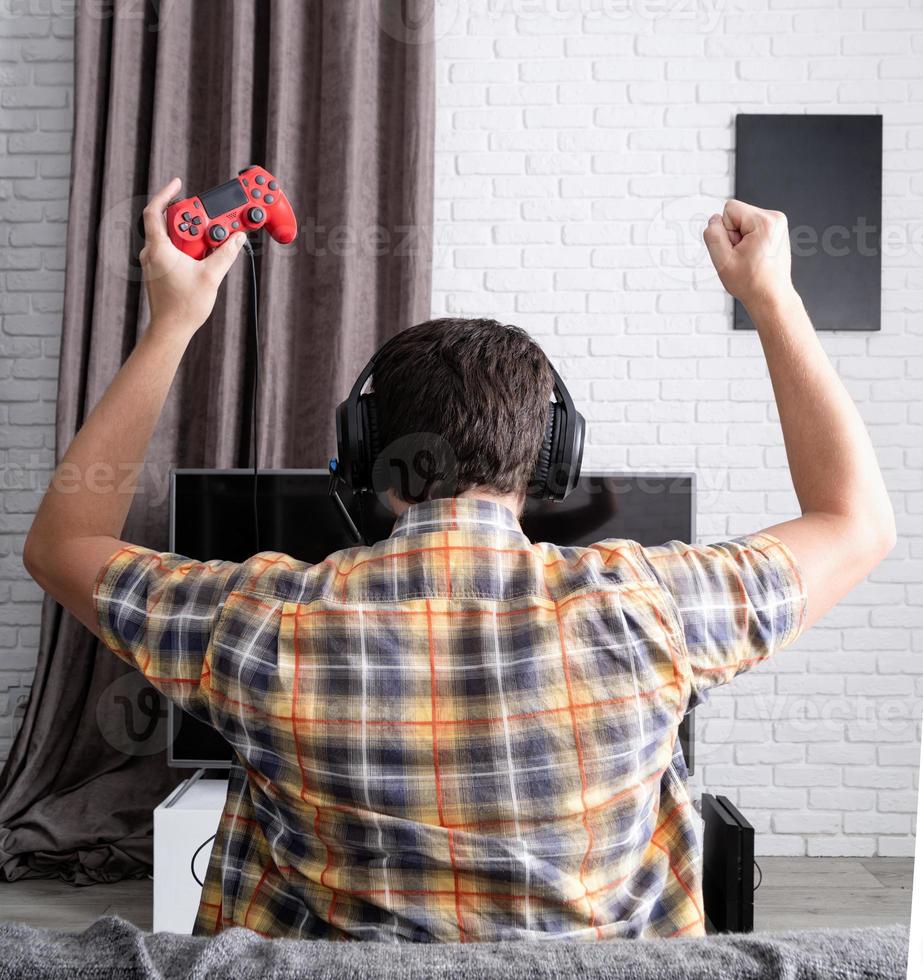 vue arrière d'un jeune homme jouant à des jeux vidéo à la maison photo