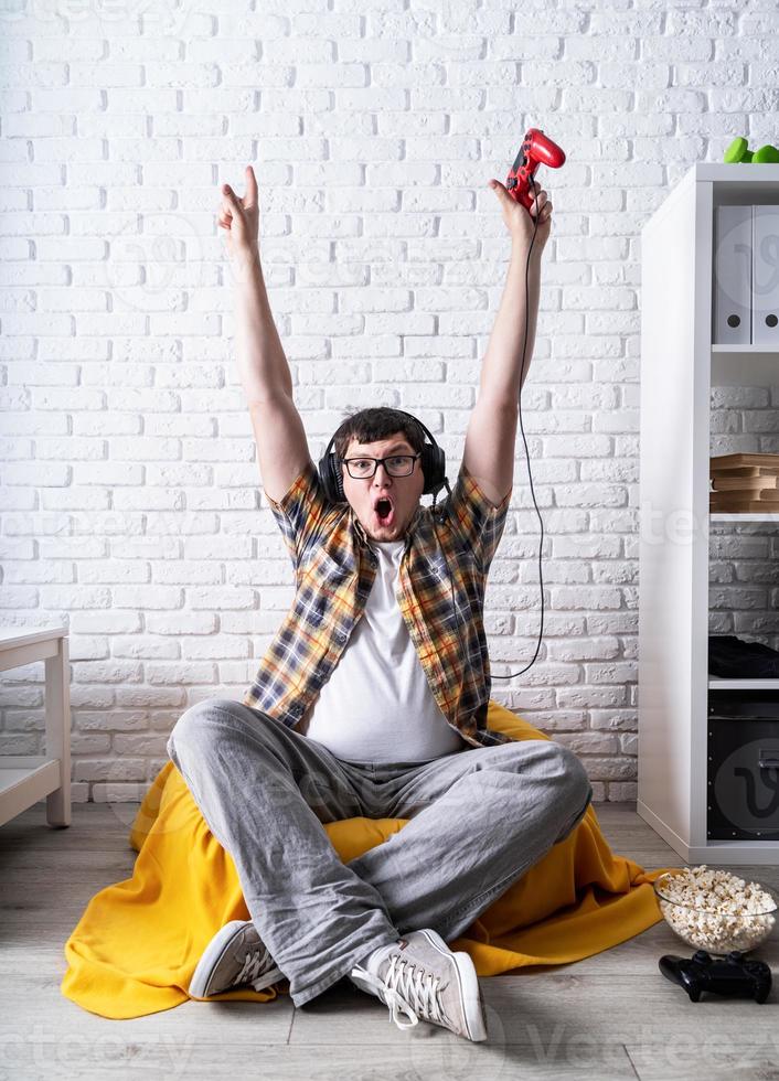 jeune homme excité jouant à des jeux vidéo à la maison profitant de sa victoire photo