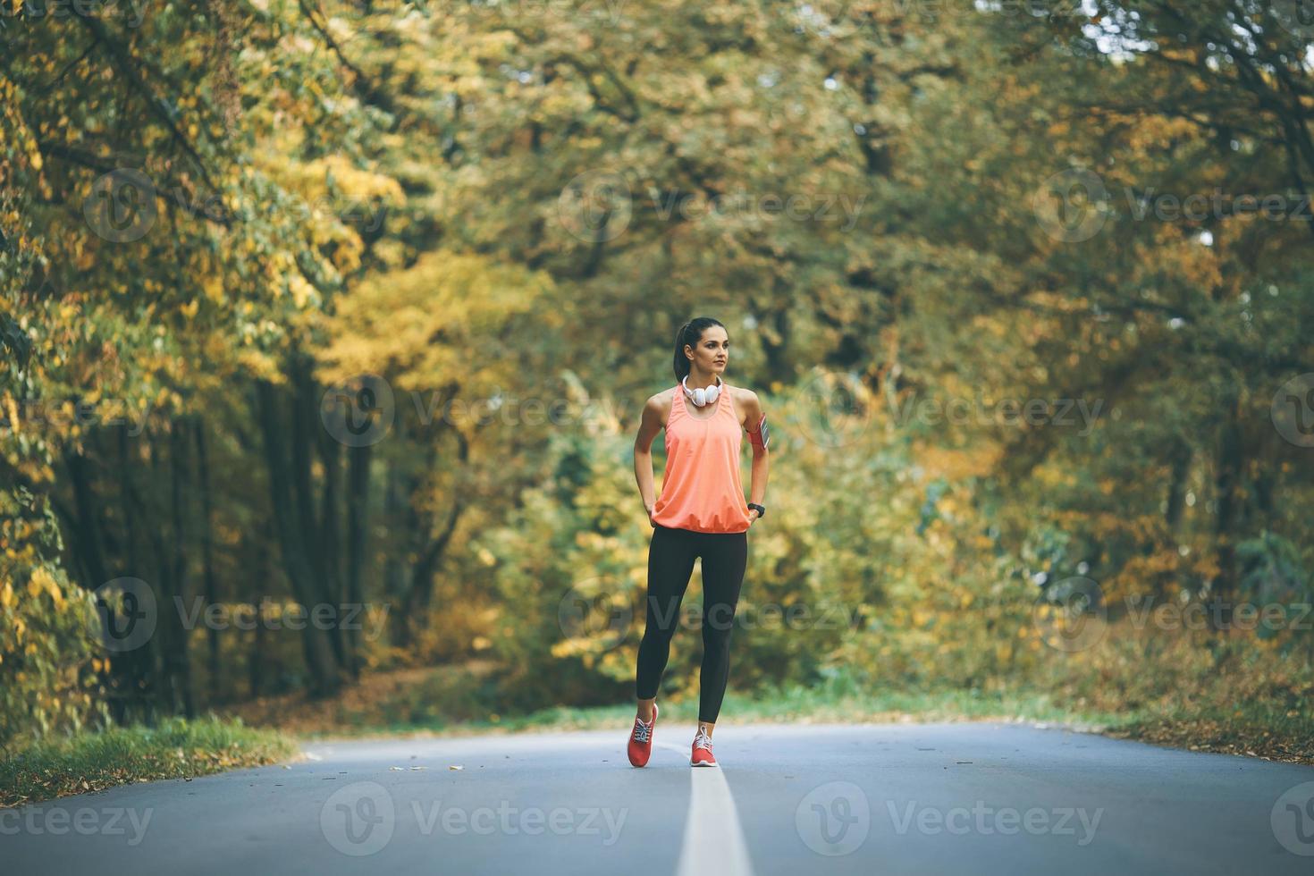 jeune femme fait une pause pendant l'entraînement dans la forêt d'automne photo