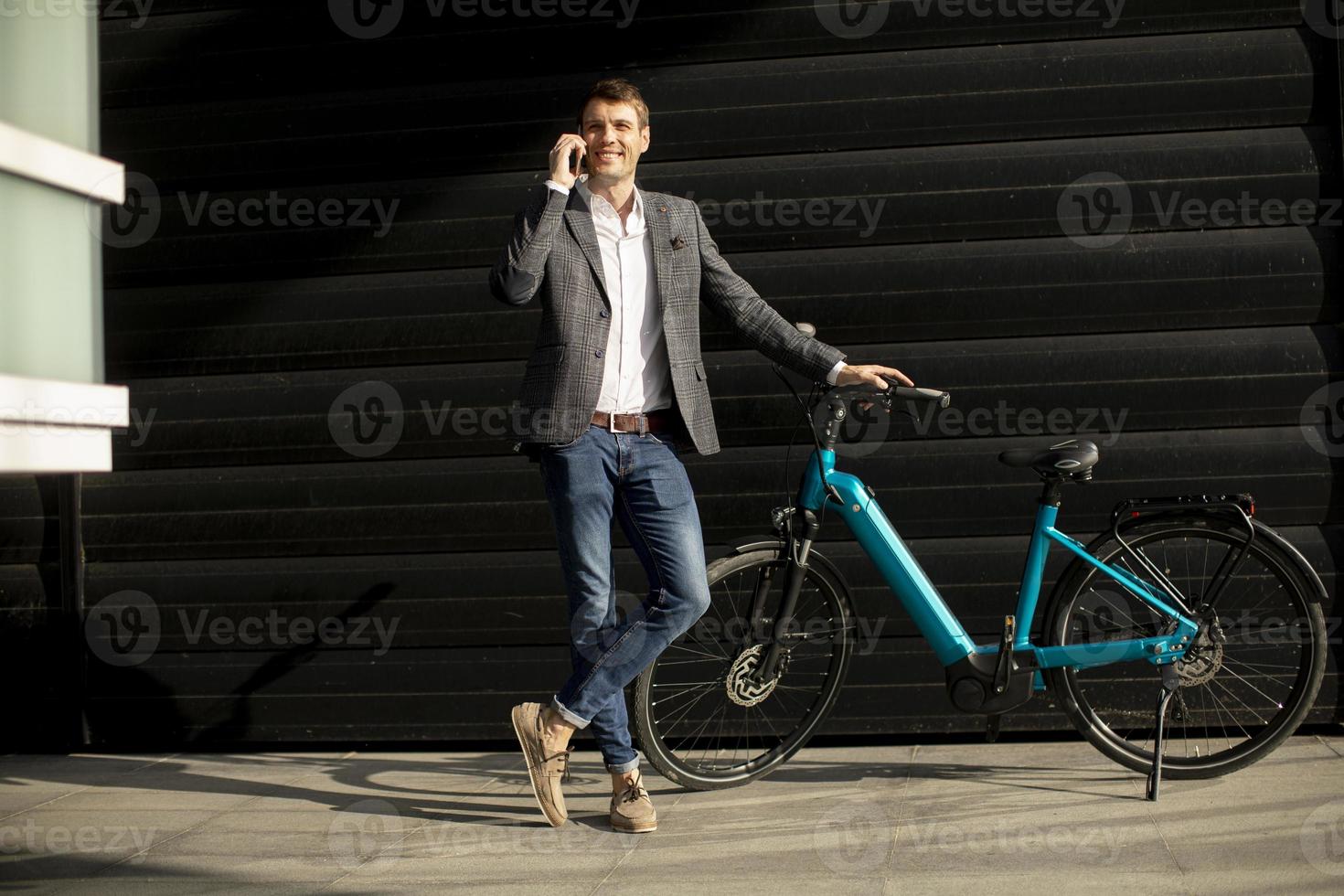 jeune homme d'affaires debout près du vélo électrique et utilisant un téléphone portable photo