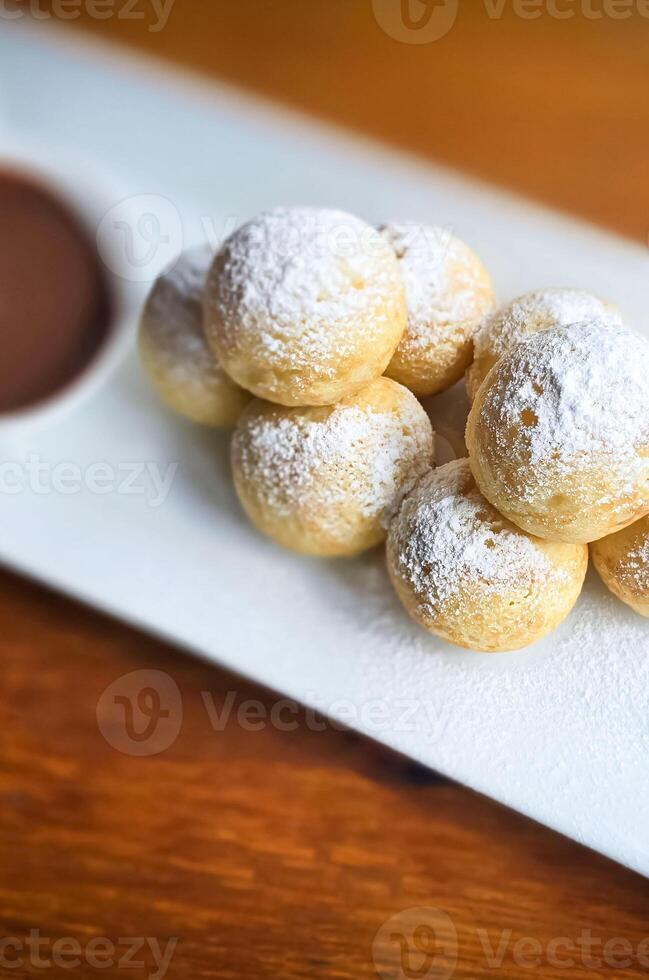 fait maison néerlandais poffertjes mini Crêpes avec glaçage en poudre sucre et Chocolat plombages avec Additionnel Chocolat sauce photo