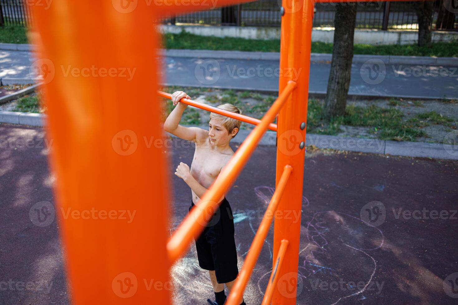 un athlétique adolescent prépare à effectuer une remonter sur le bar. rue faire des exercices sur une horizontal bar dans le école parc. photo