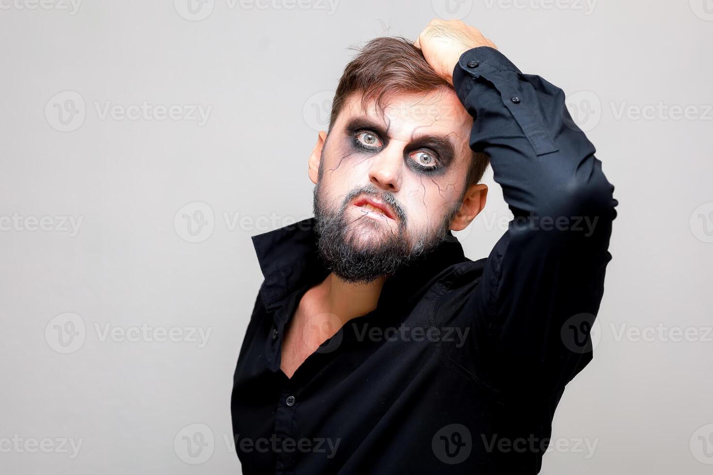 Halloween et maquillage pour une barbu homme qui larmes le cheveux sur le sien tête photo