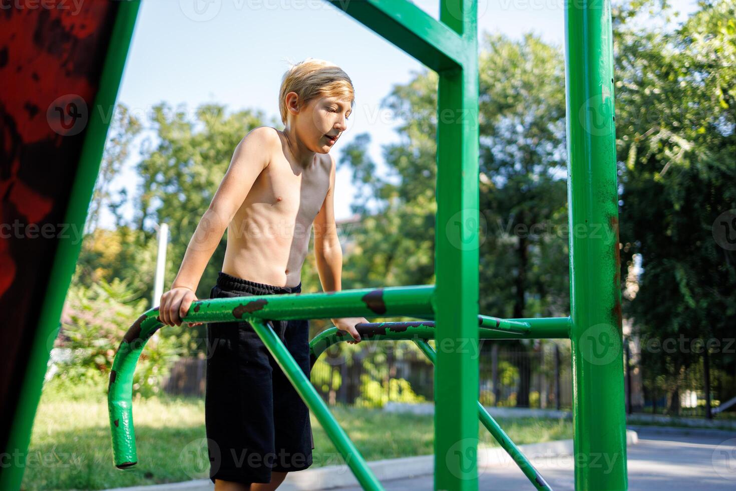 une des sports enfant effectue des pompes sur des sports barres. rue faire des exercices sur une horizontal bar dans le école parc. photo