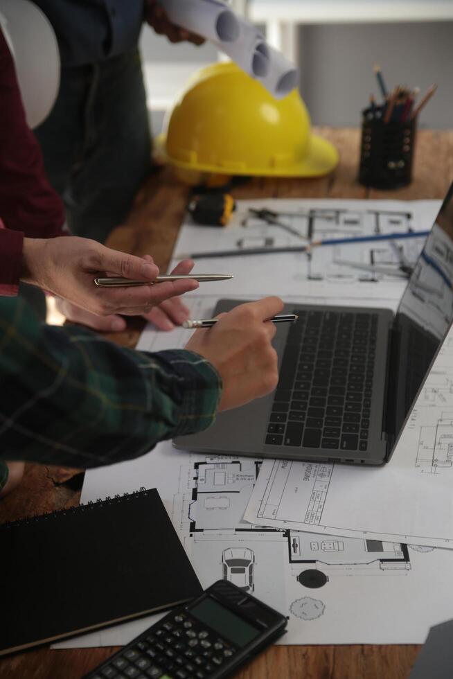 ingénieurs sont consultant le équipe à conception un architectural structure pour clients avec plans et bâtiment des modèles à travail à bureau. photo
