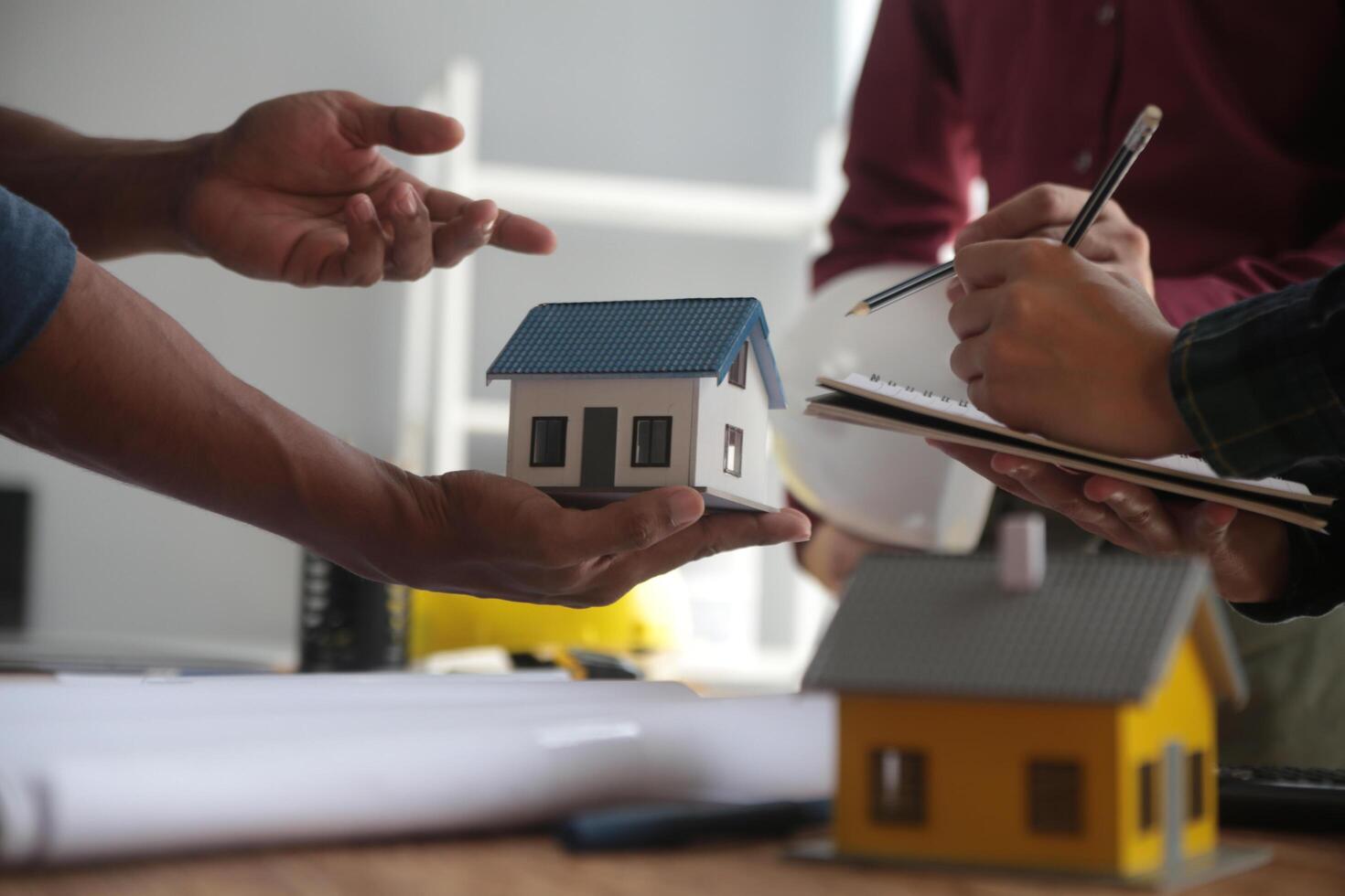 ingénieurs sont consultant le équipe à conception un architectural structure pour clients avec plans et bâtiment des modèles à travail à bureau. photo