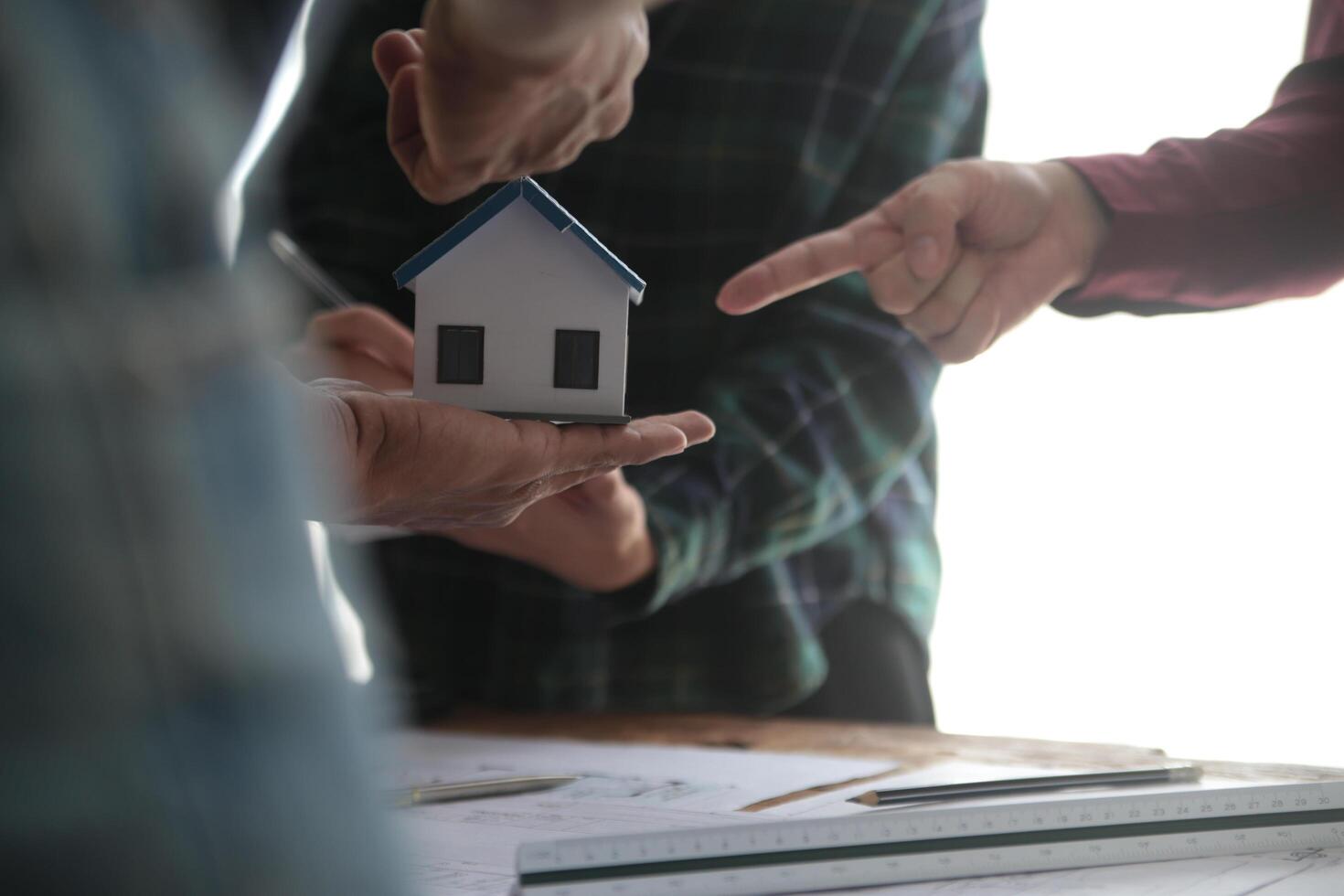 ingénieurs sont consultant le équipe à conception un architectural structure pour clients avec plans et bâtiment des modèles à travail à bureau. photo