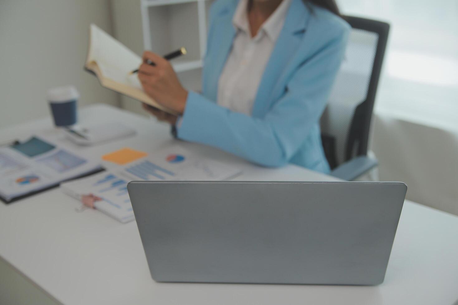 charmante jeune femme d'affaires asiatique assise sur un ordinateur portable au bureau, faisant un rapport calculant le document de vérification du service des recettes internes. photo