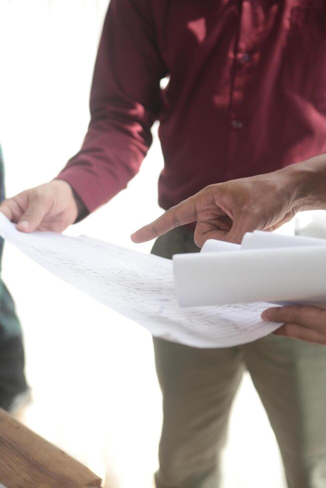 diverse équipe de spécialistes utilisation portable sur construction placer. réel biens bâtiment projet avec ingénieur investisseur et homme d'affaire vérification zone, travail sur civil ingénierie, discuter stratégie plan photo