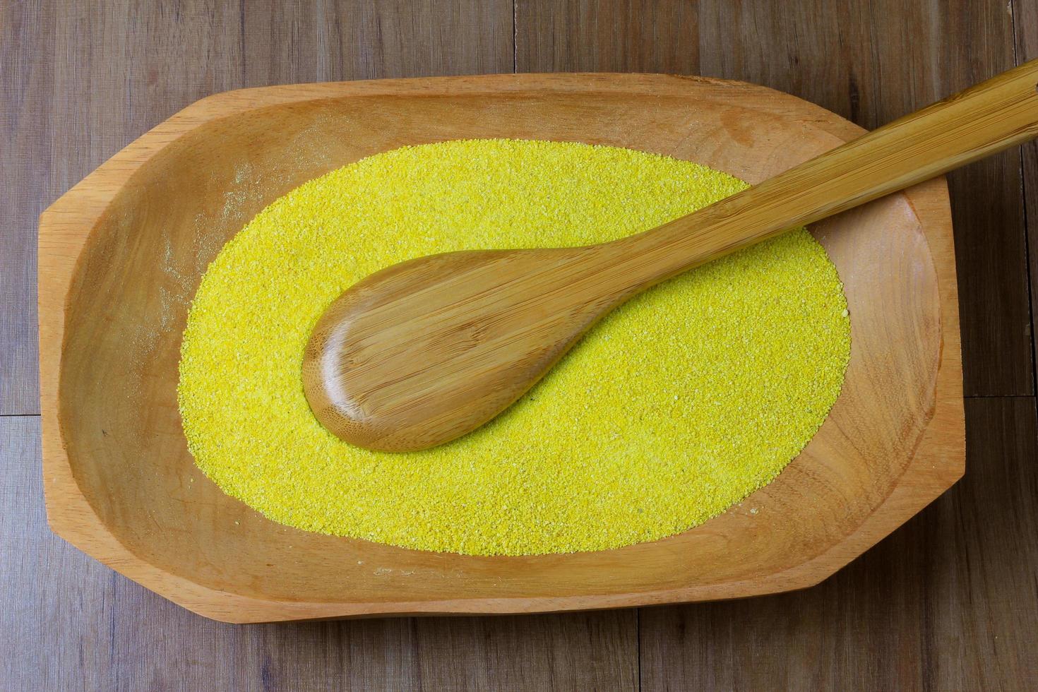 portion de farine de manioc crue jaune, bol en bois, vue de dessus de table en bois photo