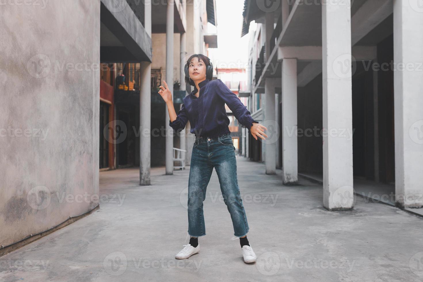 heureuse jeune femme asiatique écoutant de la musique et s'amusant avec des écouteurs dans la rue photo