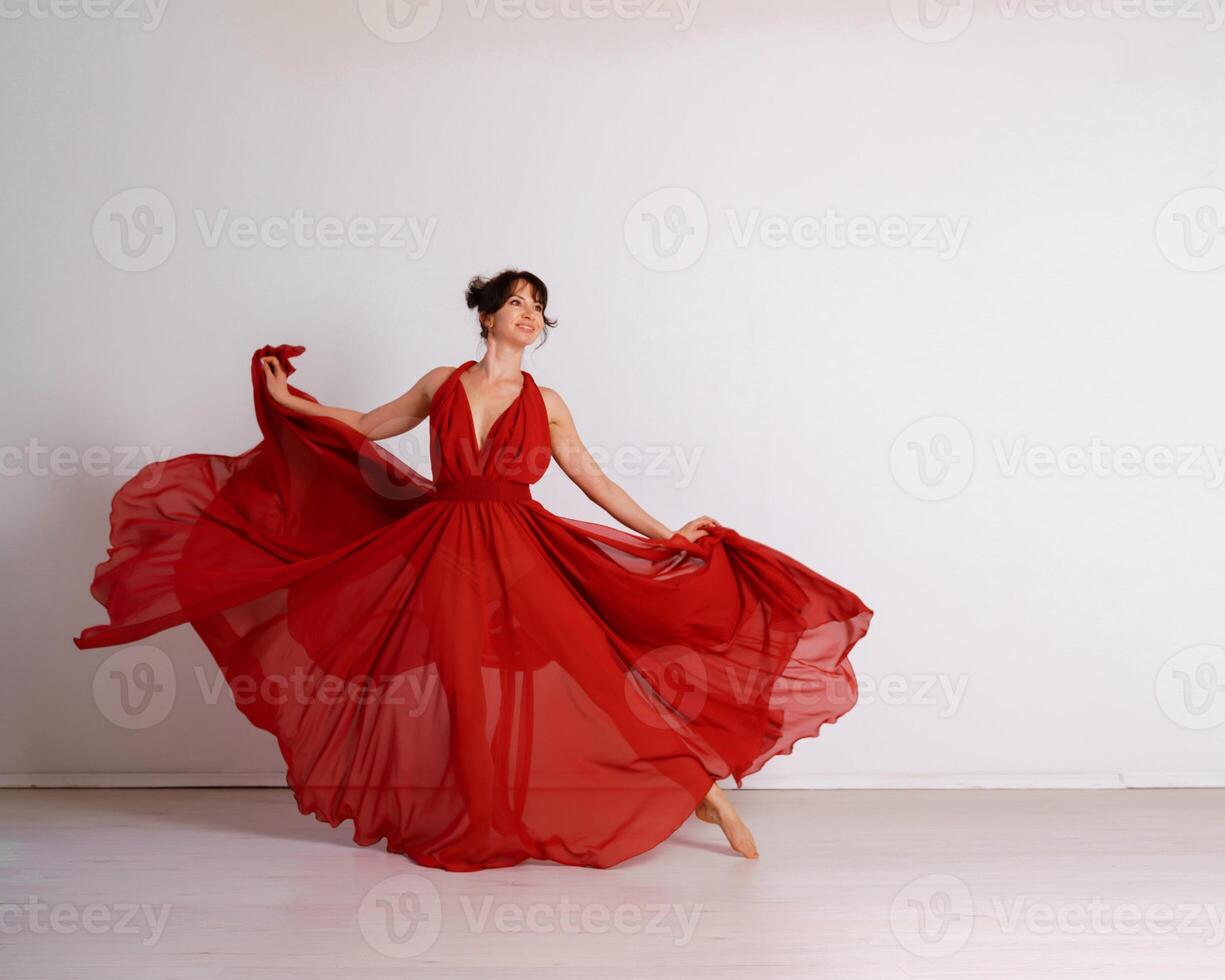 Danseur dans une rouge en volant robe. femme ballerine dansant sur une blanc studio Contexte photo