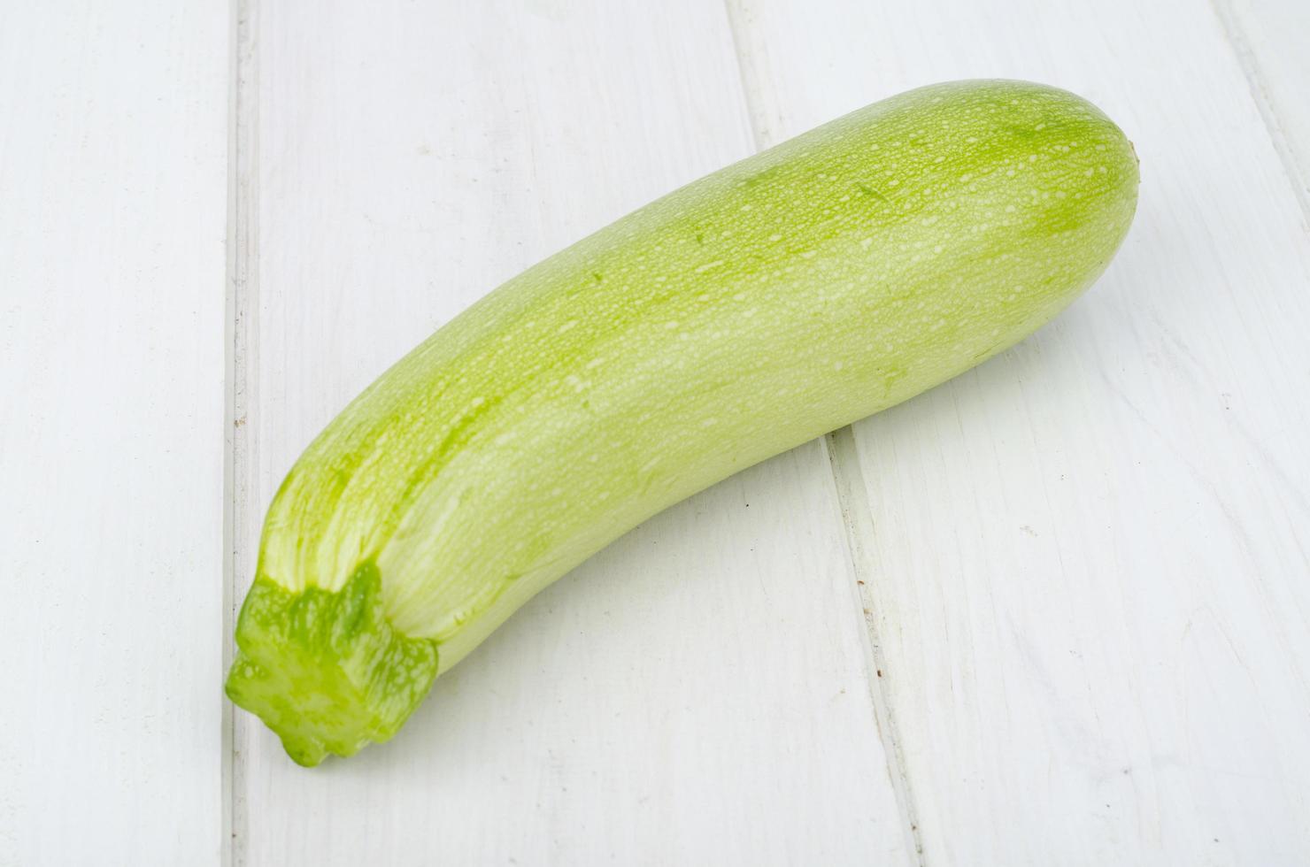 Jeunes courgettes fraîches vertes sur une table en bois pour la cuisson photo