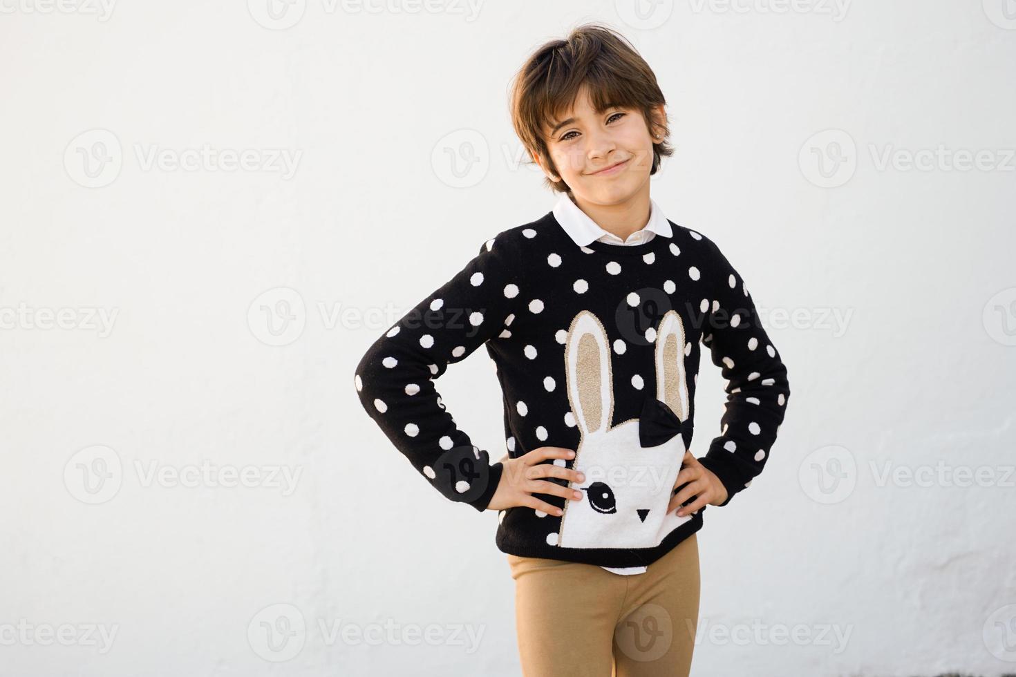 fille de sept ans aux cheveux courts souriant sur un mur blanc photo