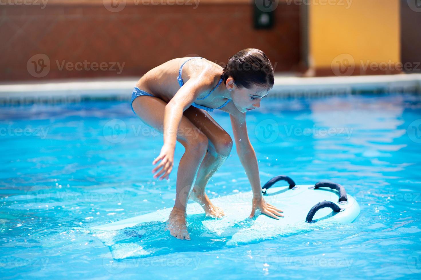 jolie fille jouant avec un bodyboard dans une piscine. photo