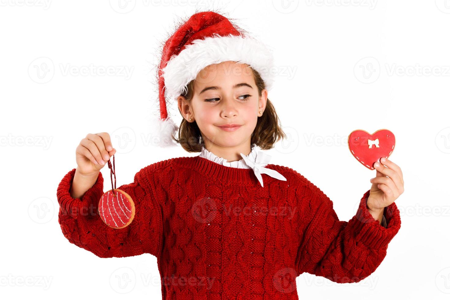 adorable petite fille portant un bonnet de noel avec des biscuits de noël photo