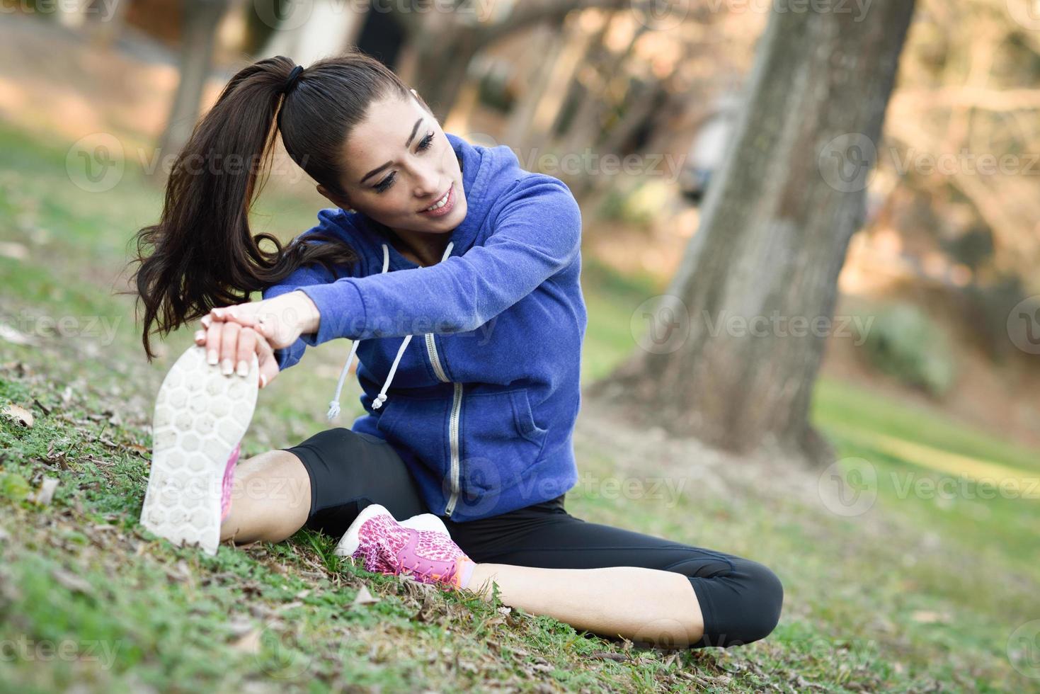 Happy young woman stretching avant de courir à l'extérieur photo