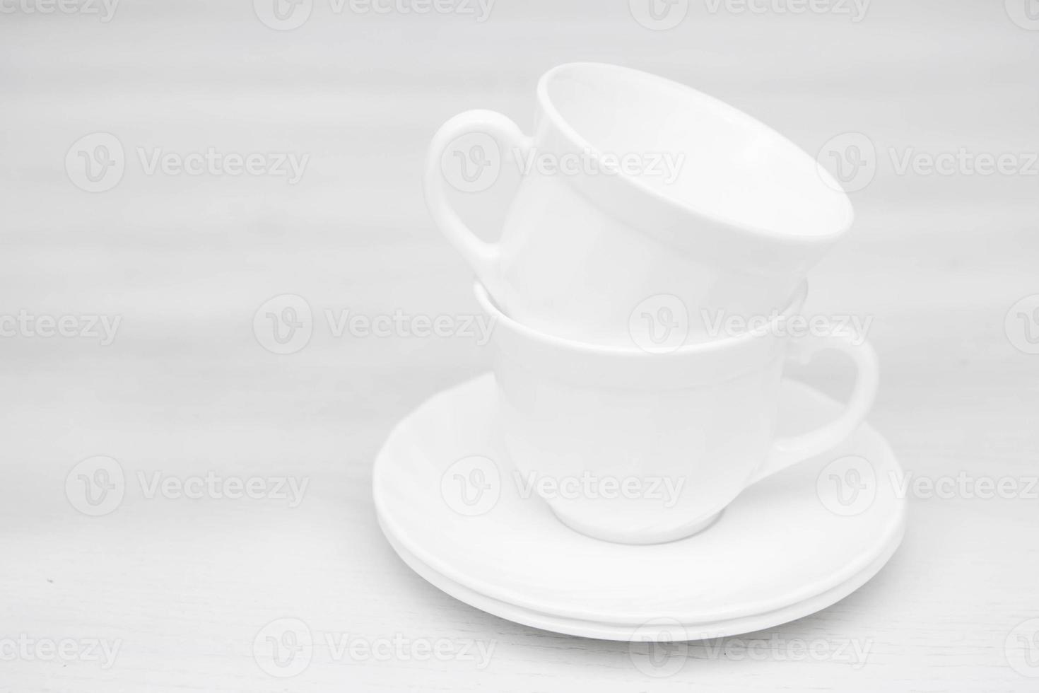 tasses en céramique blanche avec soucoupes sur table blanche photo