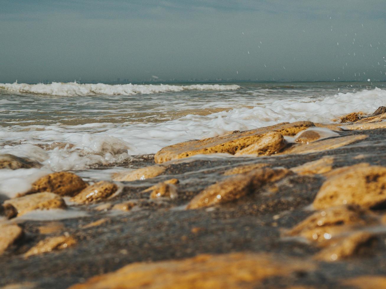 beau bord de mer avec de nombreuses pierres de mer de différentes tailles, partie sauvage de la plage, journée ensoleillée. les vagues battent contre le rivage rocheux. concept d'été. fond d'écran. haute qualité photo