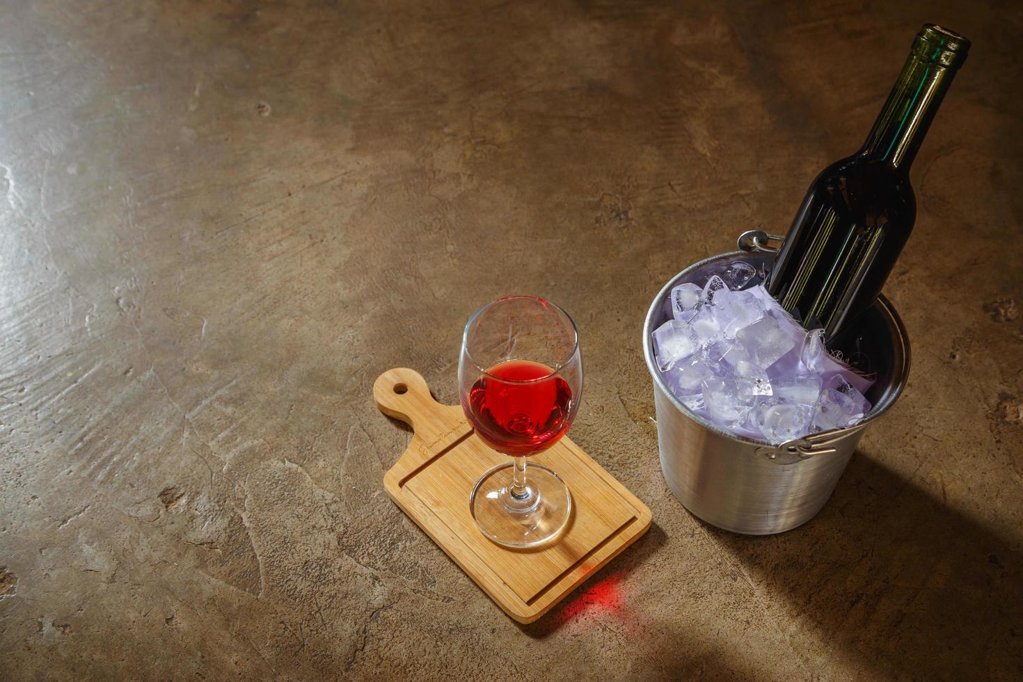 bouteille de vin rouge dans un seau à glace et un verre de vin rouge photo