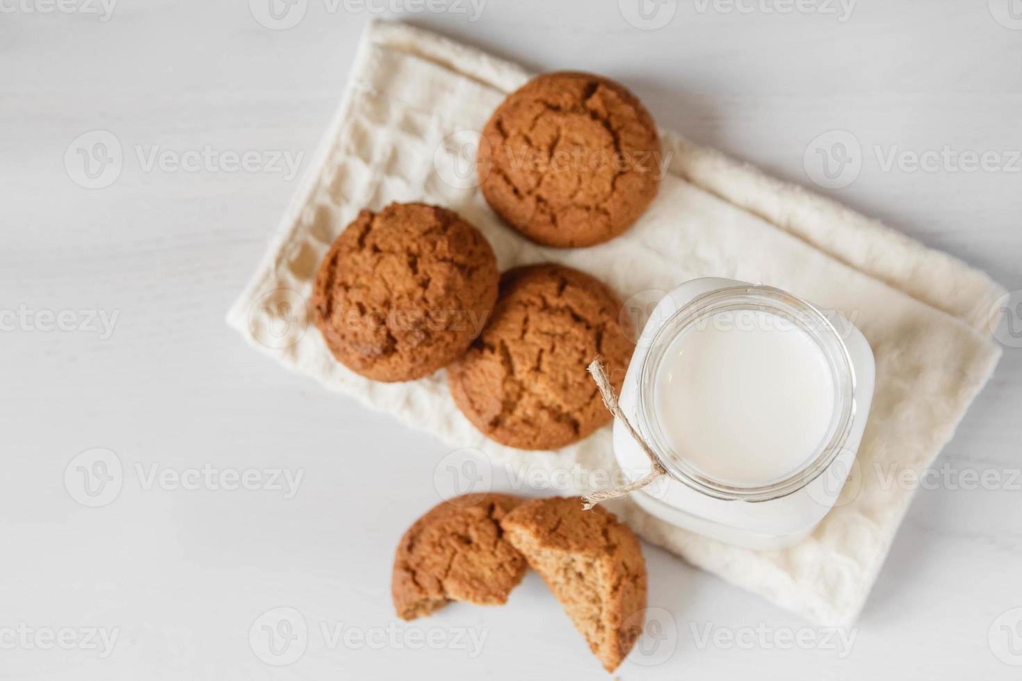 lait dans un bocal en verre et biscuits à l'avoine près d'une serviette sur un tableau blanc photo