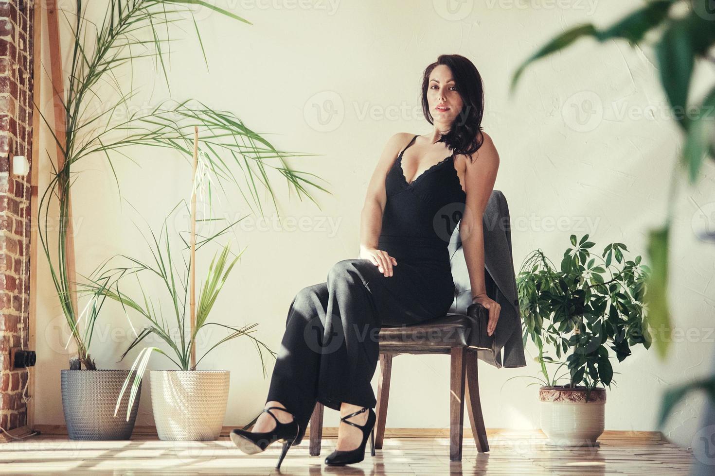 femme vêtue de vêtements noirs est assise sur une chaise dans un intérieur de style loft photo