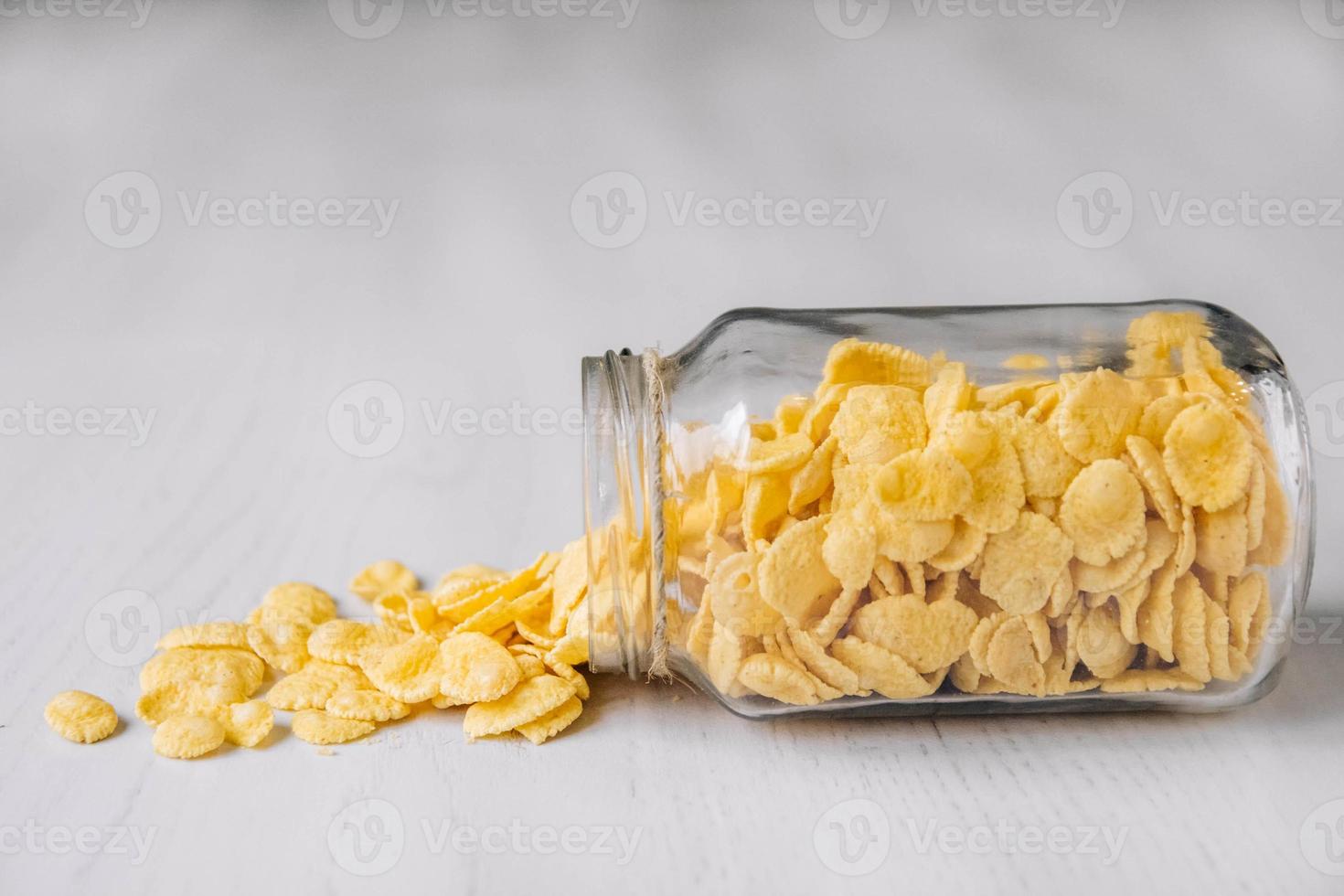 flocons de maïs dans un bocal en verre sur une surface en bois blanche photo