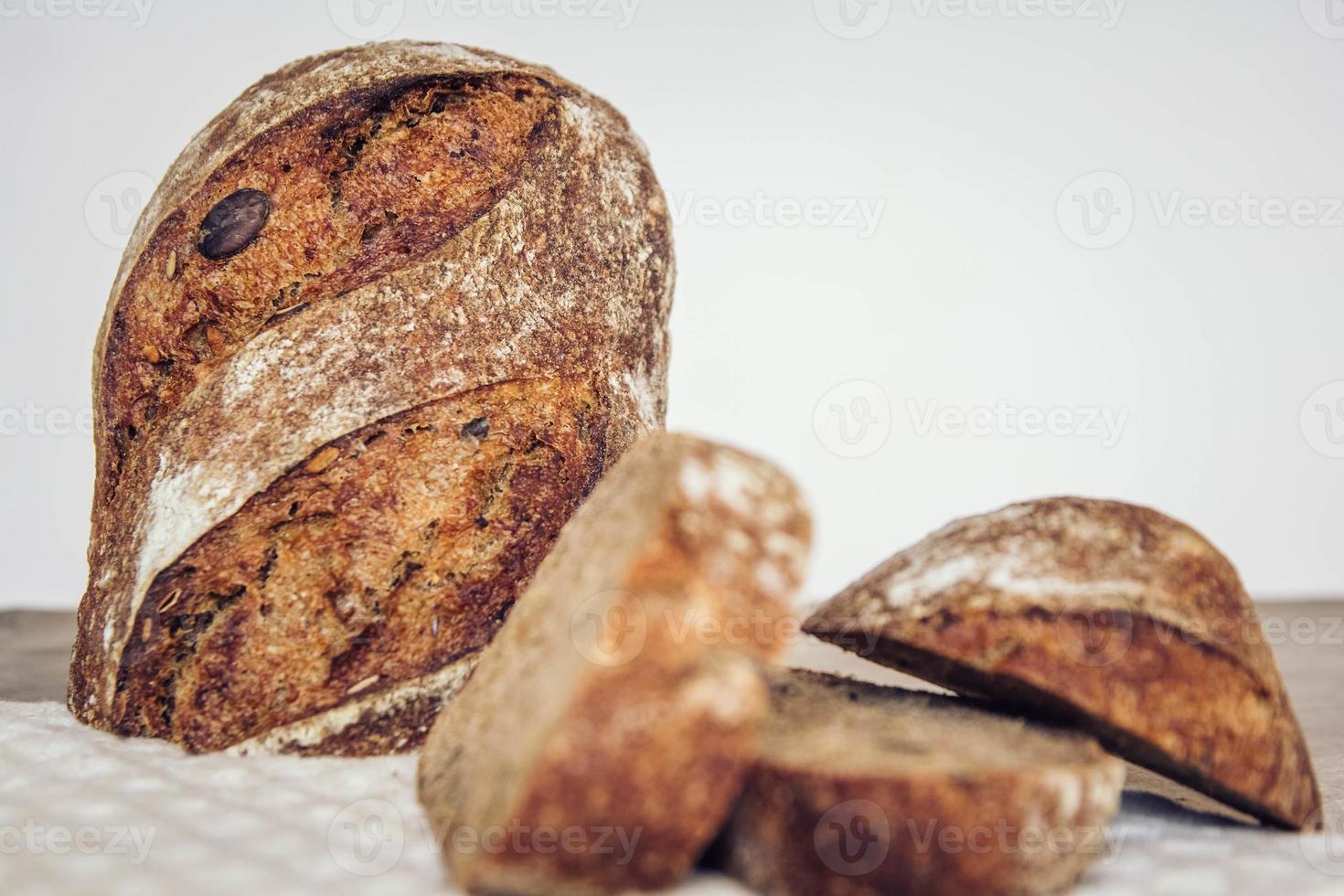 pain frais brun avec des graines sont coupés en morceaux sur fond de bois ancien photo