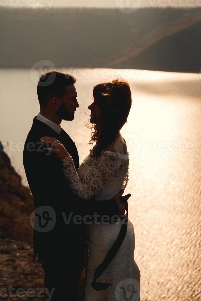 couple de mariage, la mariée et le marié se tenant la main sur un fond de montagnes et de rivières photo