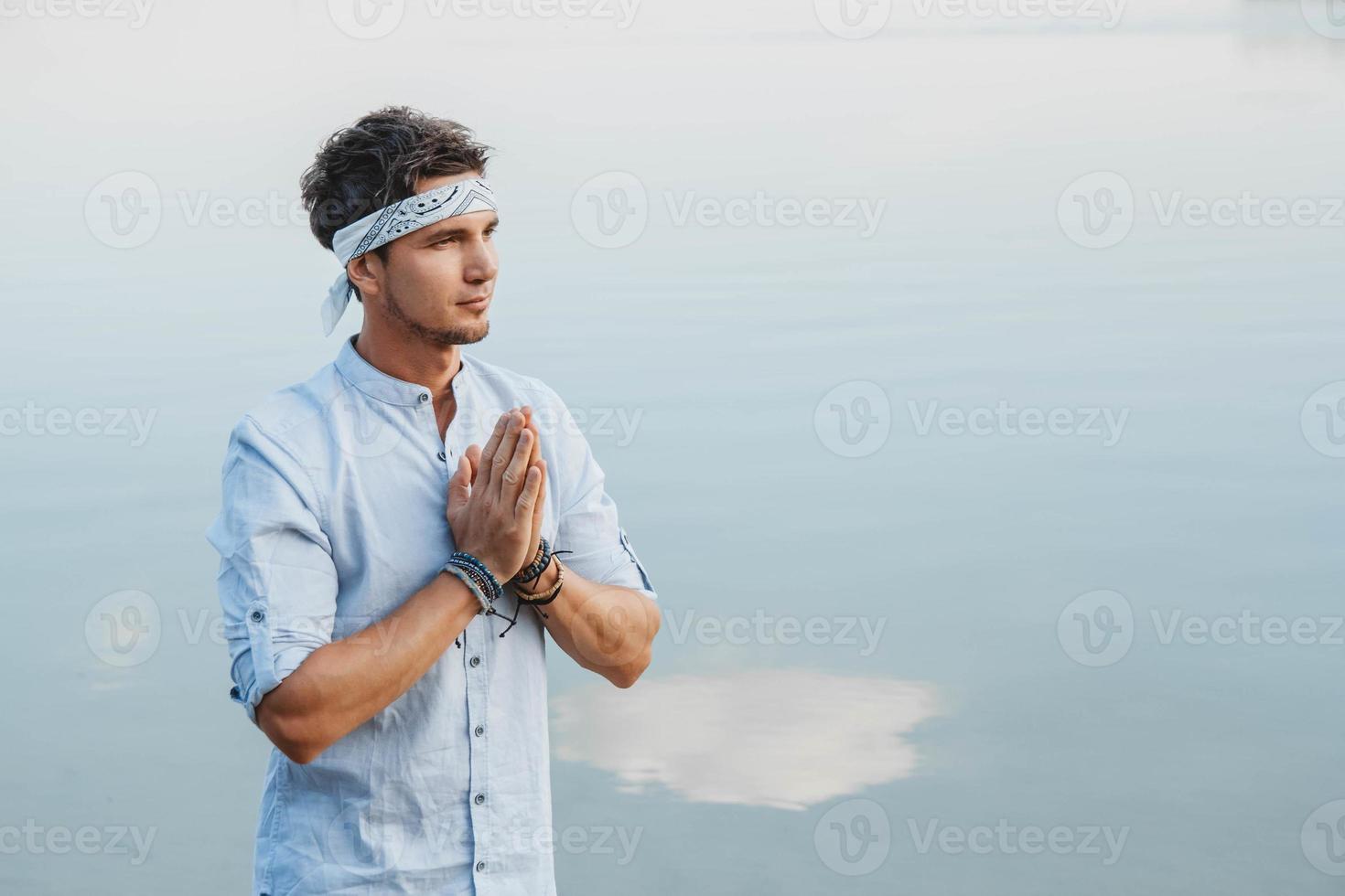 homme tenant la main en prière sur fond réflexe de l'eau du ciel bleu photo