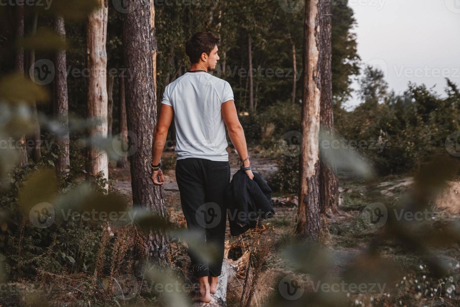 L'homme posant à l'extérieur dans la forêt se tient pieds nus sur un journal photo