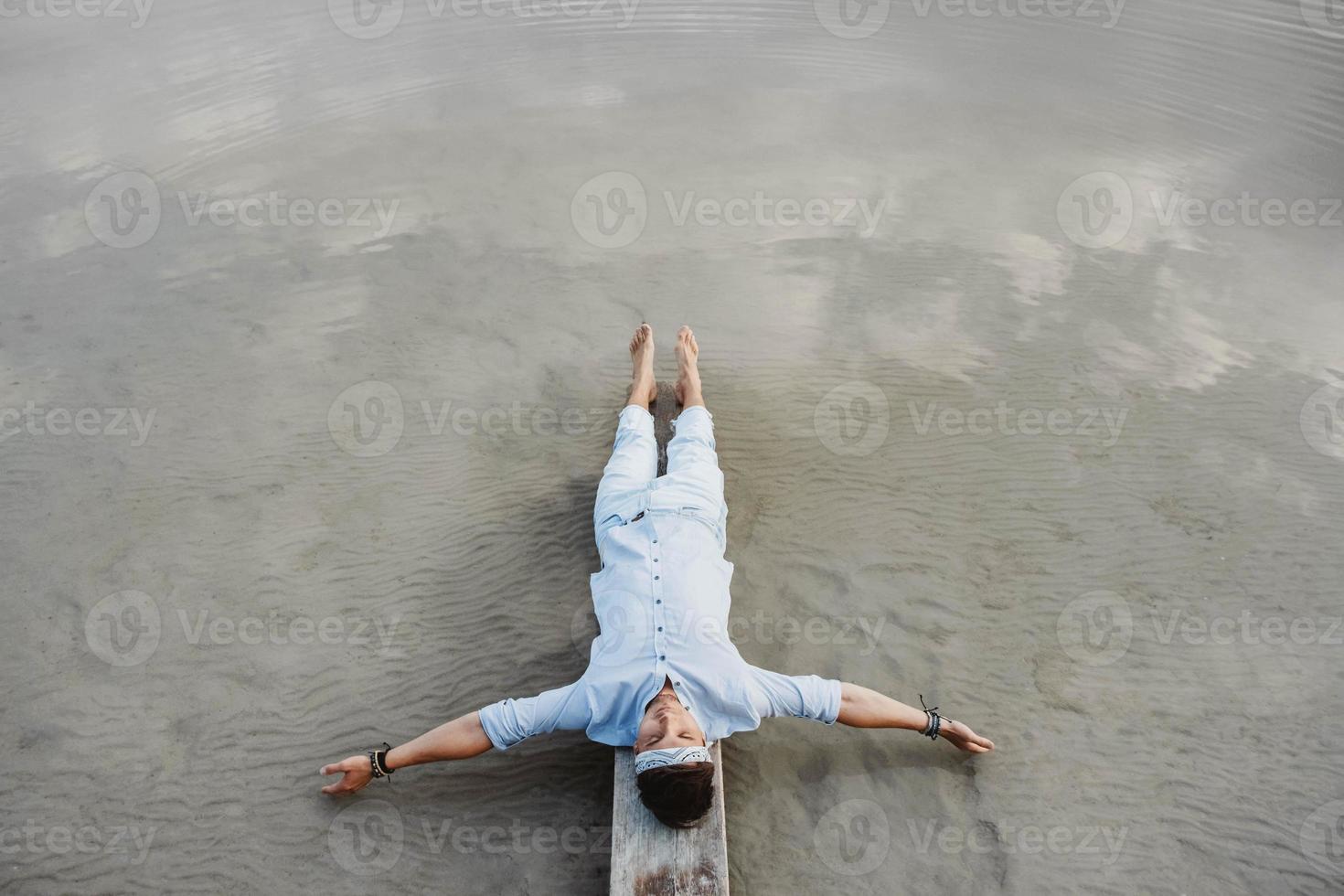 Homme allongé sur un pont en bois sur fond d'eau photo