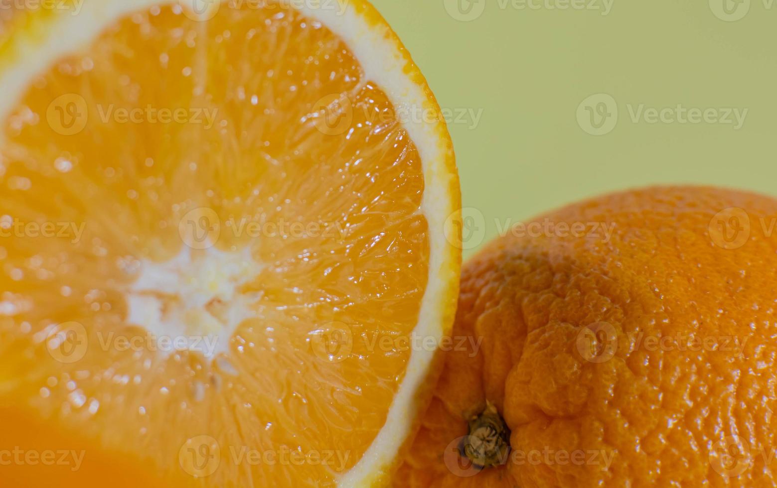 orange coupée en deux près d'une orange entière sur fond vert photo