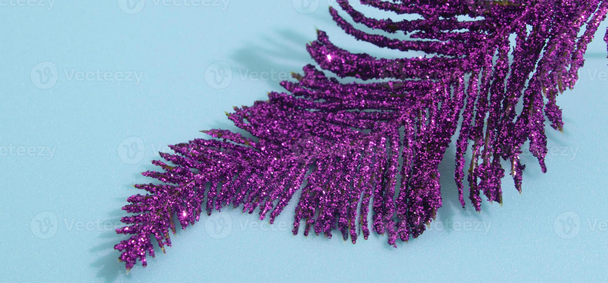 plume violet brillant décoratif de noël en paillettes sur fond bleu format bannière photo