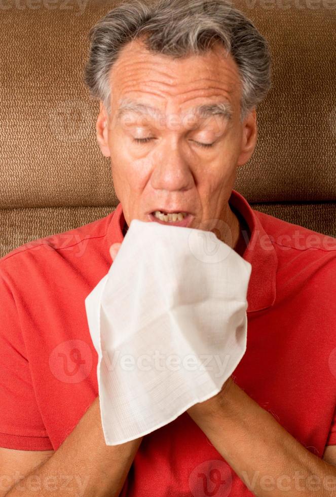 homme avec la grippe éternuant dans un mouchoir à sa maison photo