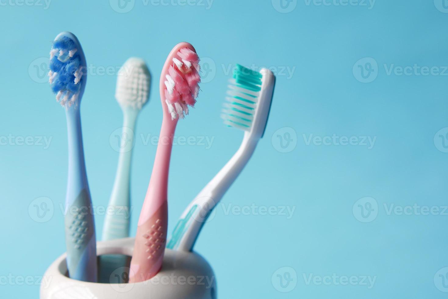 Brosses à dents colorées dans une tasse blanche contre un mur photo